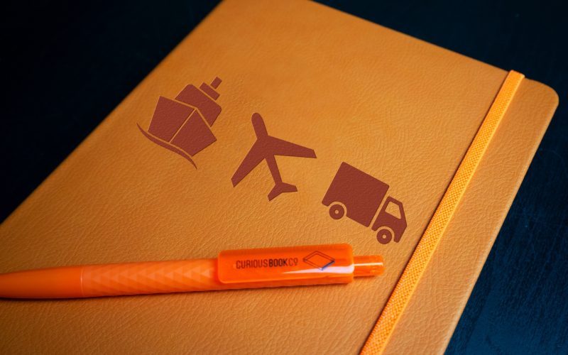 Example of a bespoke orange notebook - embossed with boat, plane and truck