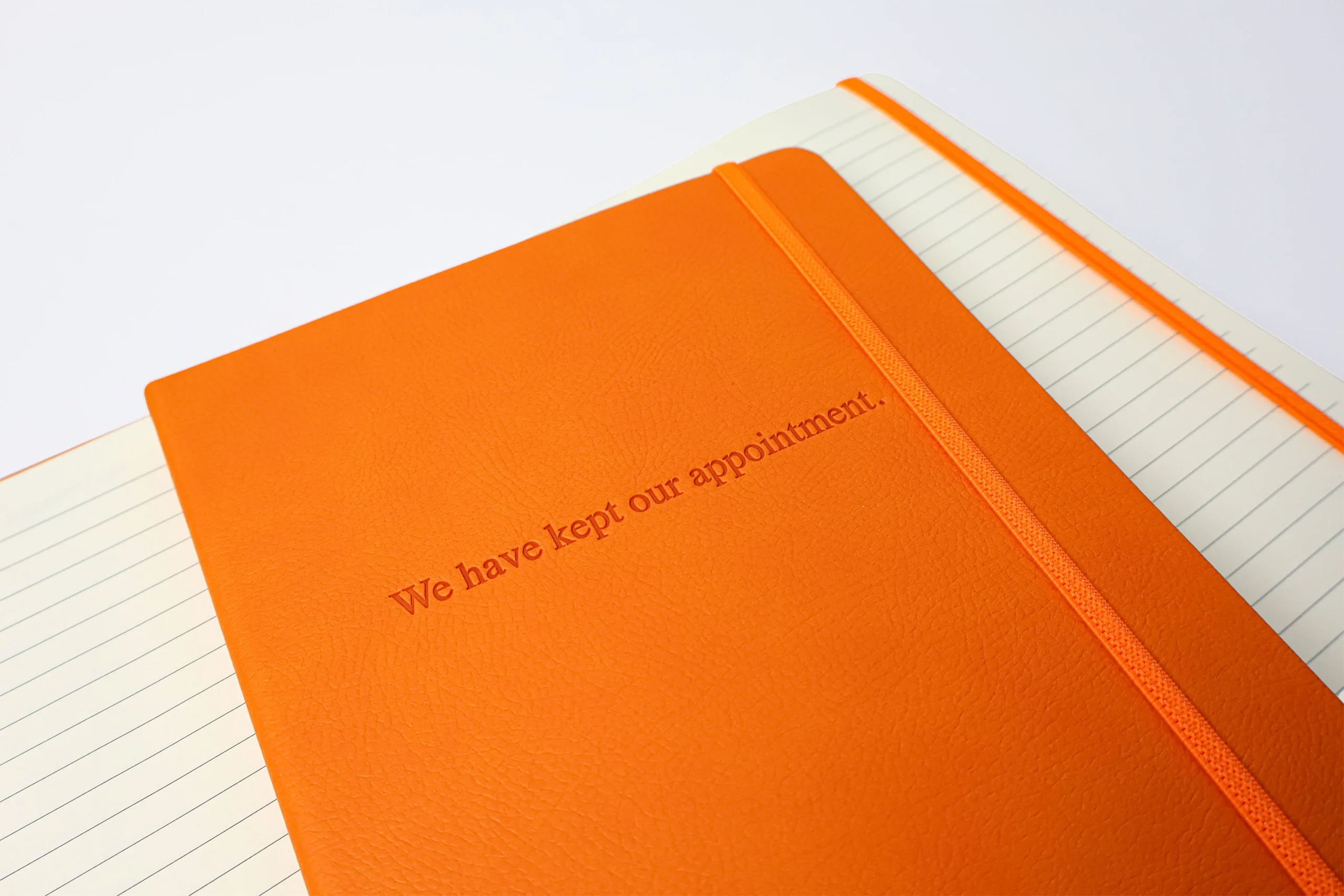 Custom notebook for Waiting For Godot in orange with debossed text on front cover.