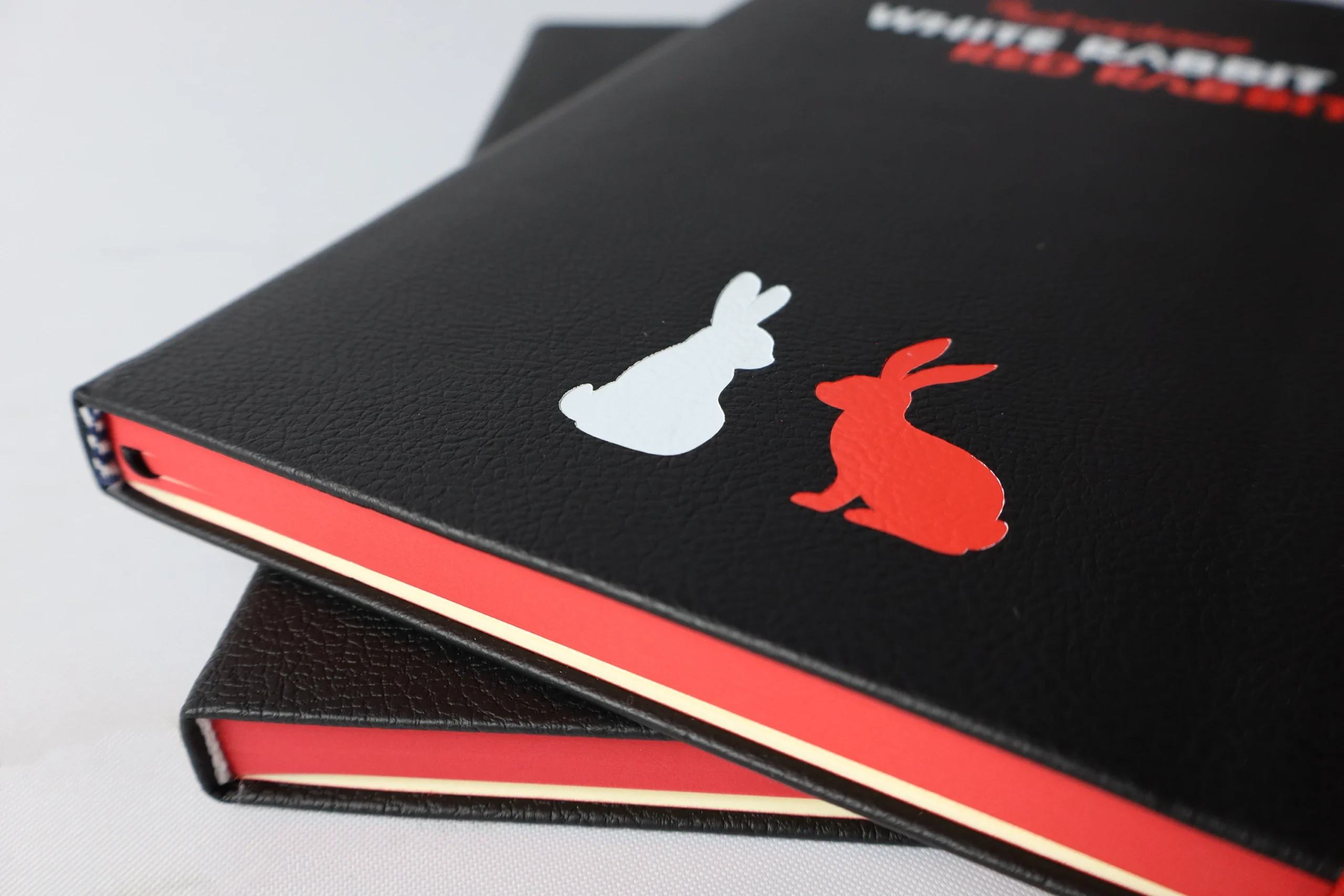 Custom bespoke notebook for White Rabbit Red Rabbit, with coloured foil printed rabbits on the front cover.