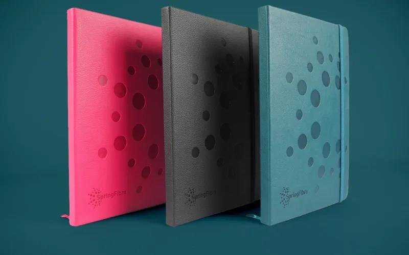 Three bespoke notebooks for Spring Fibre in pink, black and teal.
