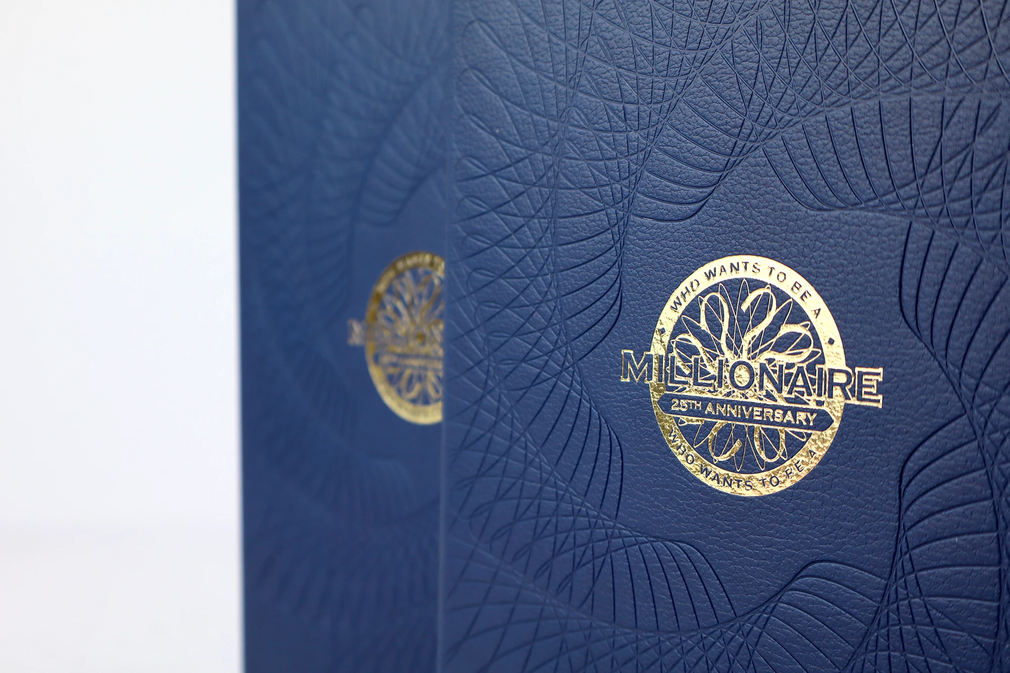 Bespoke notebooks for who wants to be a millionaire. they have a full page debossed pattern and gold foil printed logo in the center of the cover.