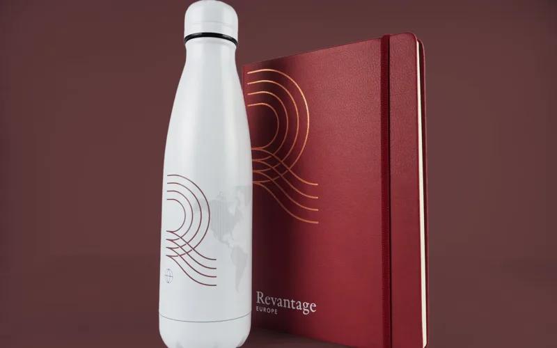 Custom notebook and branded water bottle for Revantage. The notebook is dark red with copper and white foil print.